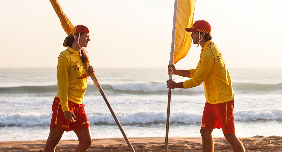 Surf Life Savers holding red and yellow flags.