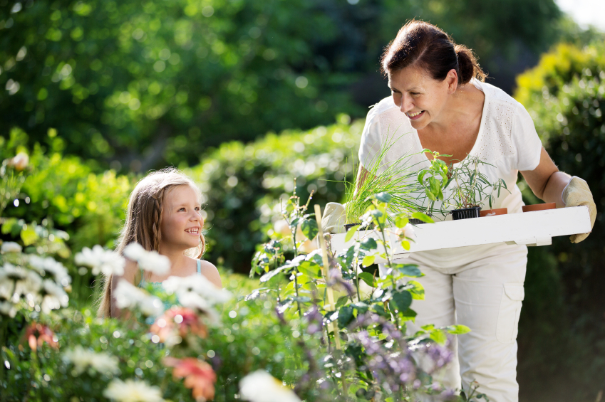 Girl and mother planting herbs in garden